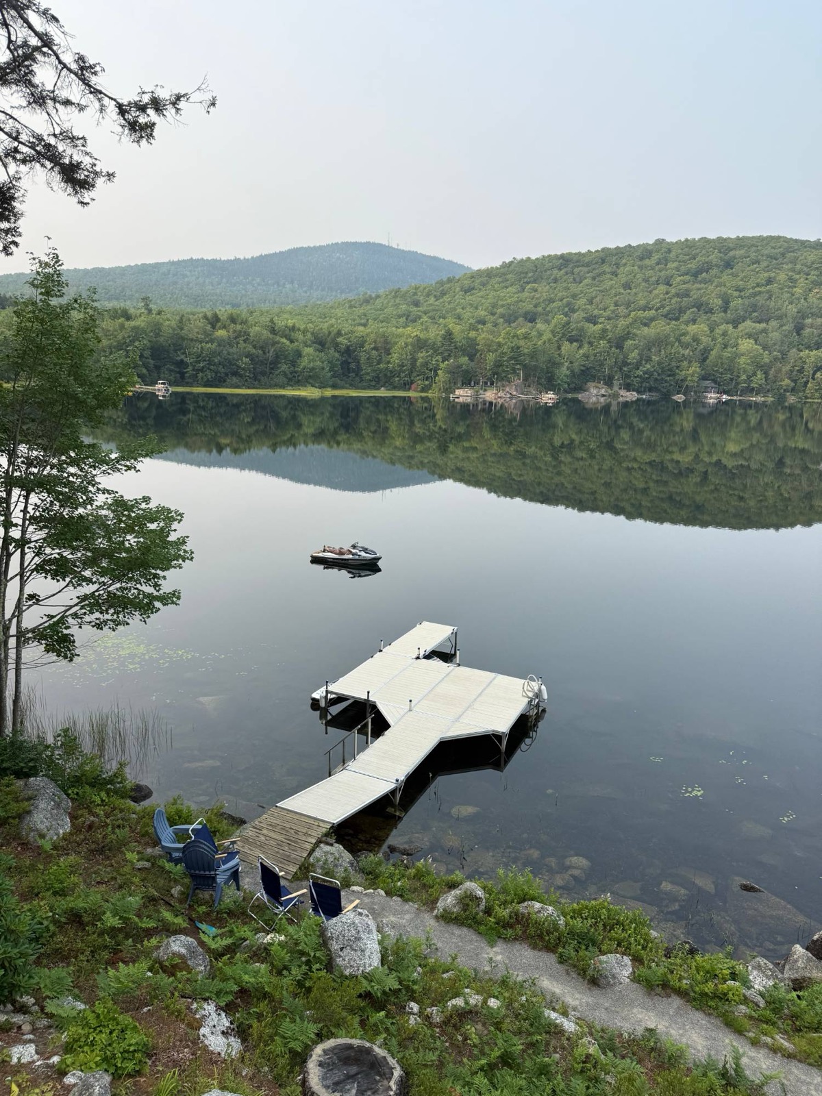 Maine lake with dock, jet ski, and mountain view at first light